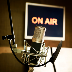 Podcasting Microphone with On Air Sign in the background.